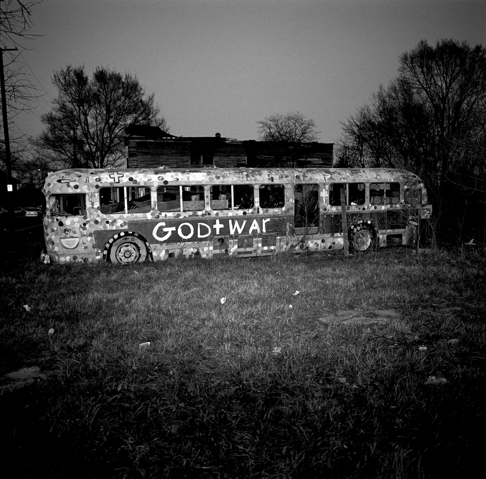 An abandoned bus in an empty lot.