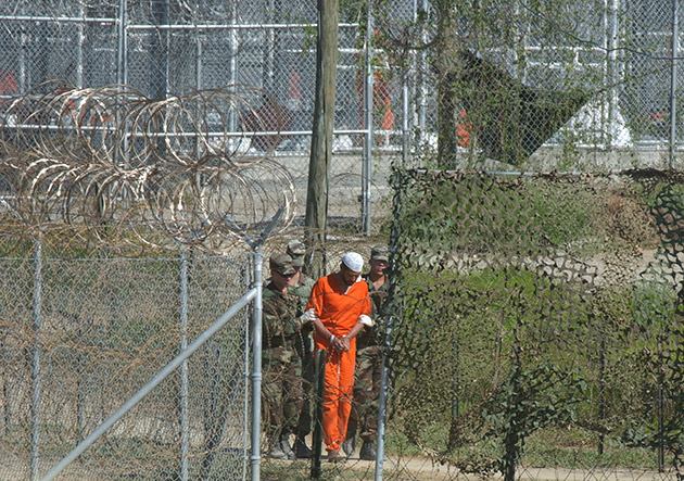 FILE - In this March 1, 2002 file photo, a detainee is escorted to interrogation by U.S. military guards at Camp X-Ray at Guantanamo Bay U.S. Naval Base, Cuba.