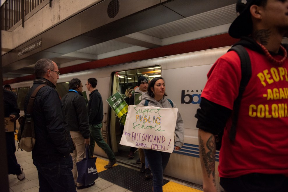 Teachers from Roots Academy in Oakland, Calif., hold signs as they exit the subway downtown.