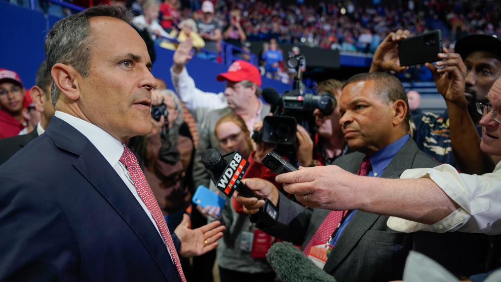 Matt Bevin talks to reporters at a colorful rally in an arena.