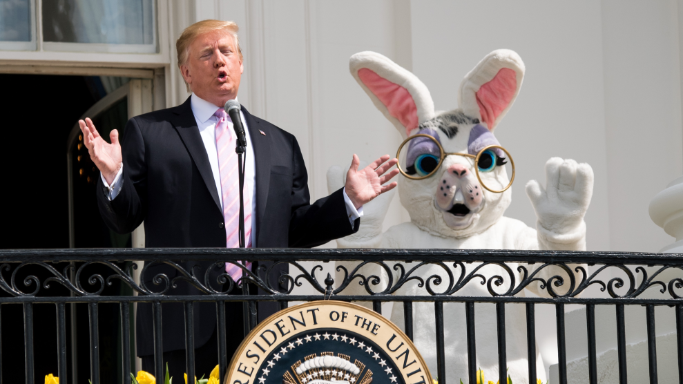 Donald Trump speaks from a White House balcony with an Easter Bunny mascot waving behind him.