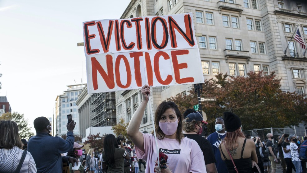 A woman holding a sign with EVICTION NOTICE written on it, stands at Black Lives Matter Plaza near the White House