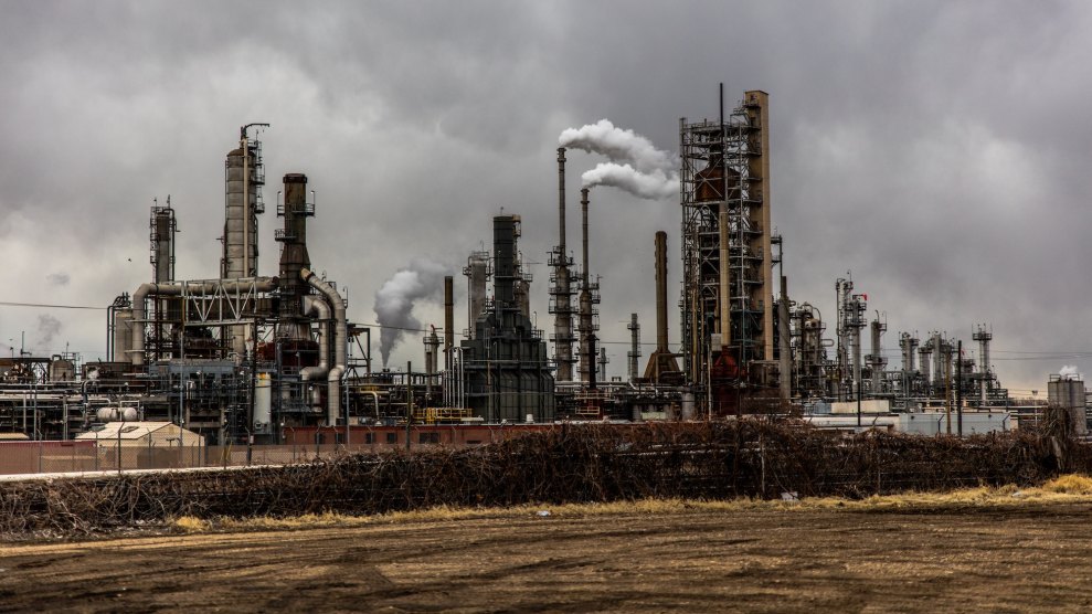 A photo of a factory that is surrounded by smoke. The sky is gray in the background.