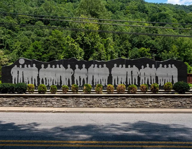 A monument that includes the silhouettes of miners standing together on a dark background.