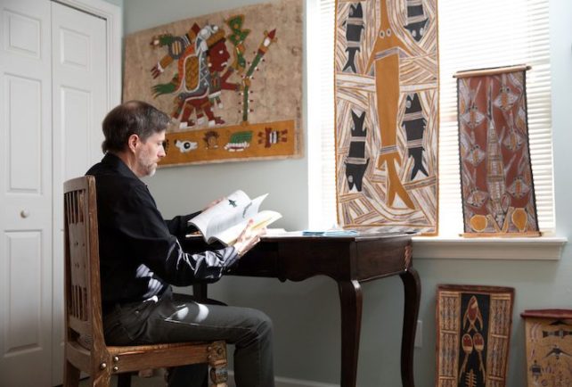 McDavitt, sitting down at his desk, flipping through a book