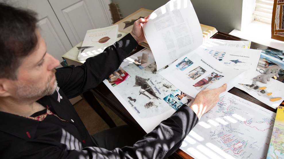 Matthew McDavitt, a white man with brown hair, sitting down and flipping through papers of fish and related documents at a desk.