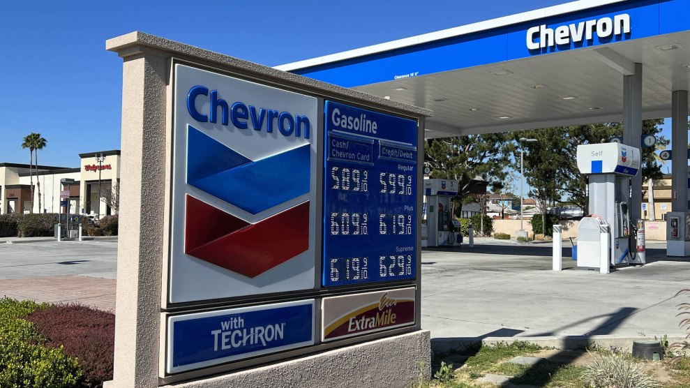 A sign at a Chevron market showing expensive gas prices, with the top of a building saying Chevron also visible