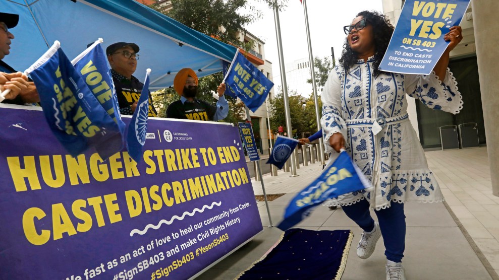 A small group waves flags and holds banners calling for an end to caste discrimination outside the California capitol.