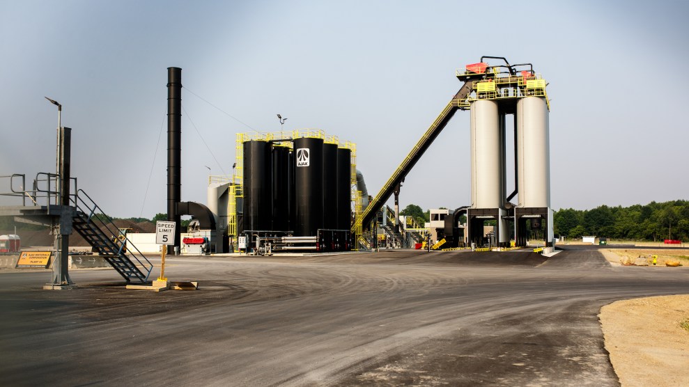 An asphalt plant, with a cloudy sky behind it.