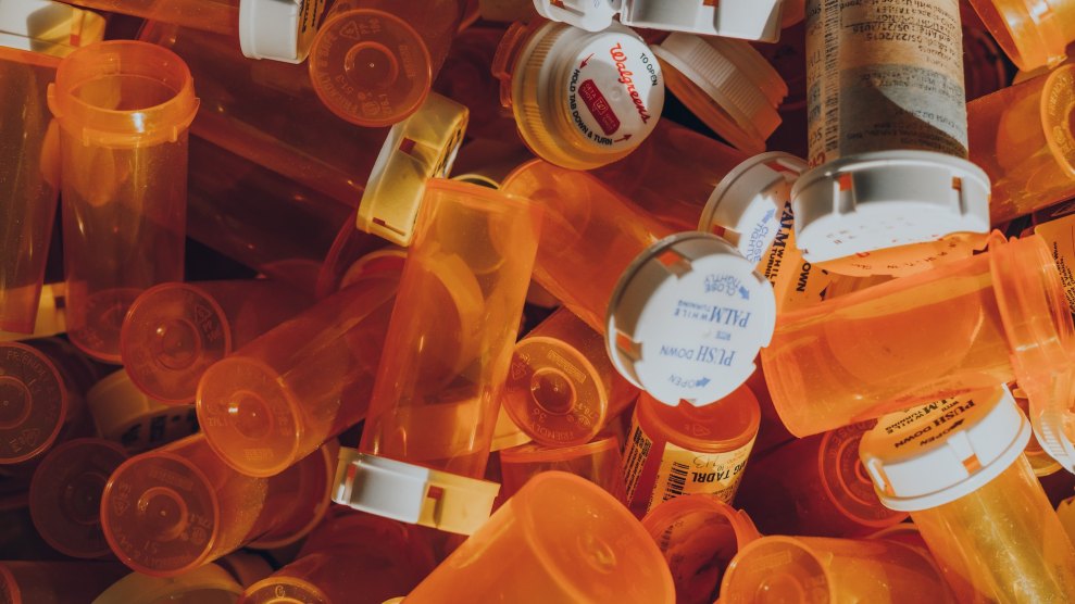 A bunch of empty orange pill bottles on top of each other, most have instructions to push down and turn on them, and one has a Walgreens logo on it.