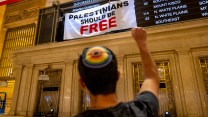 A person with a rainbow yarmulke raises their right fist to a banner that says "Palestinians Should Be Free."