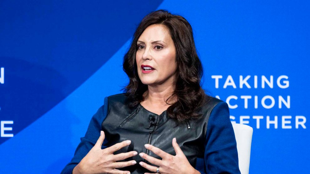 Gretchen Whitmer, a white woman with brown hair in a leather jacket, speaking at an event.