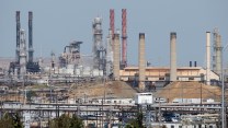 A refinery with small buldings in front of it – the sky is a blueish gray color