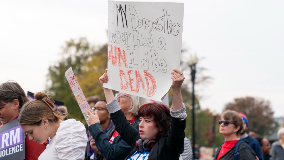 Person stands outside Supreme Court with a sign that reads, "If my domestic abuser had a gun, I'd be dead."