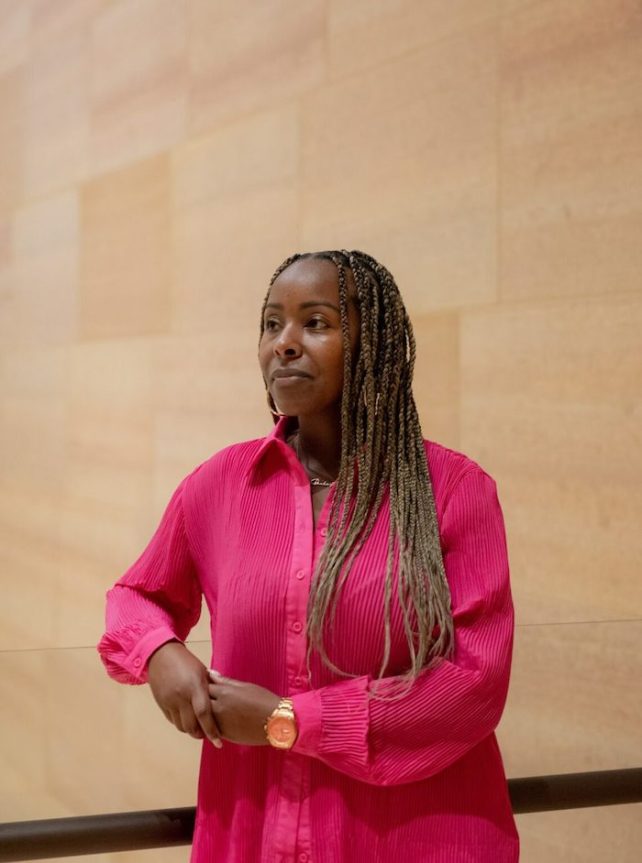 Dr. Nia Imani Bailey, a Black woman in a hot pink shirt. 