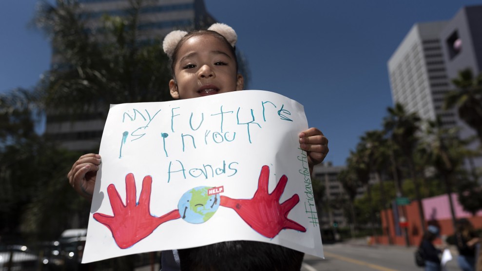 A child with light brown skin and pom poms in her hair on her dads shoulders, with a sign.