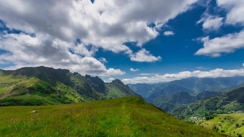 Landscape of a green hilly area on a sunny day with some clouds in the sky