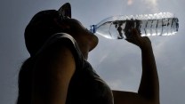 A person drinking from a plastic water bottle outside