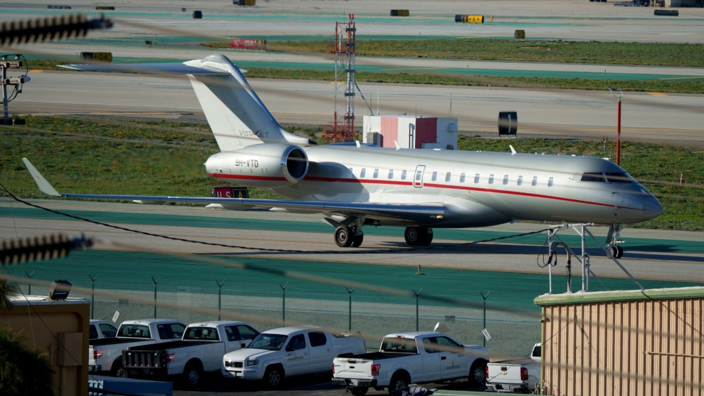 A small silver airplane sits on a green runway.