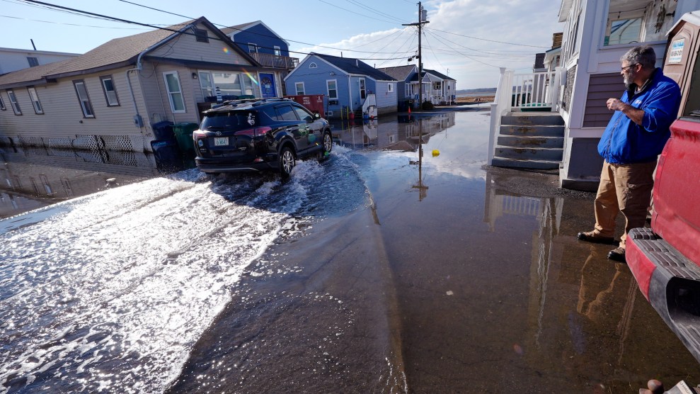 Flooding surrounding homes and cars, with a person watching outside