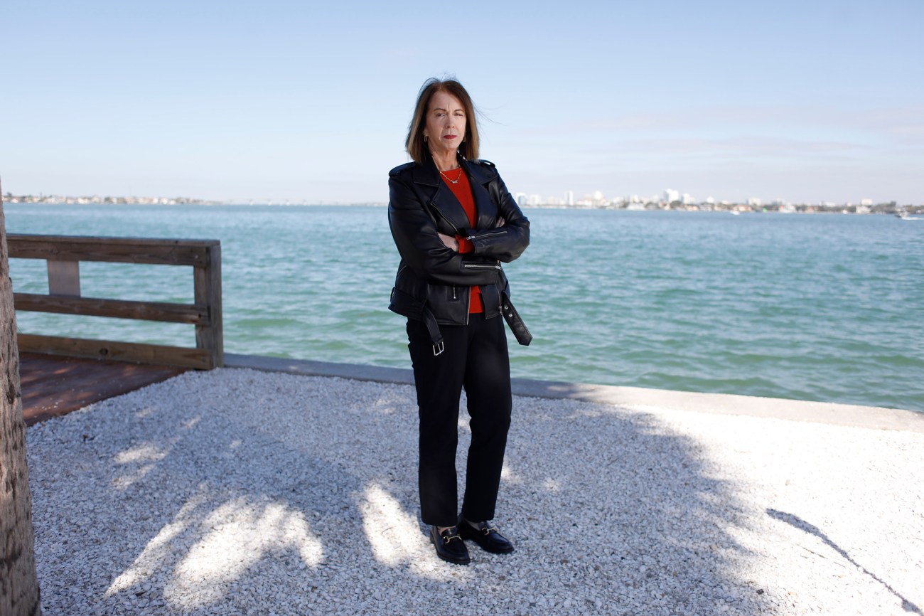 Portrait of a woman with her arms crossed standing near water.