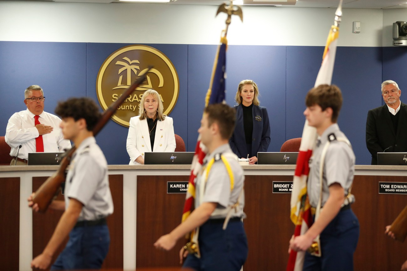 People stand as boys carrying flags walk past.