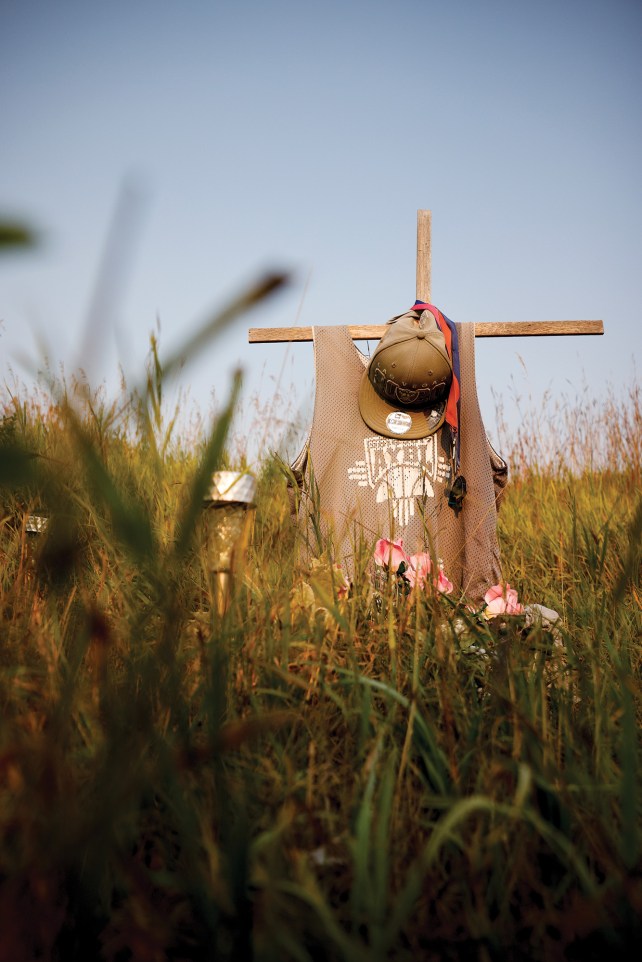 Cross memorial with a hat hanging on it. 