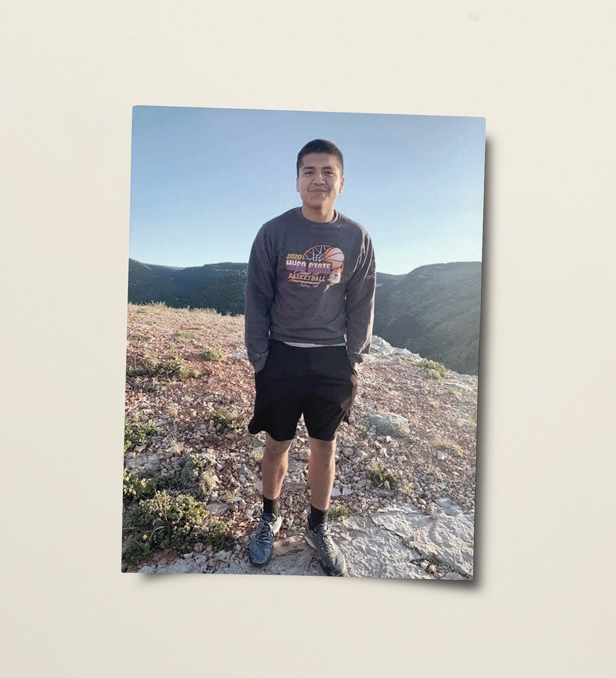 Photo of a boy smiling with his hands in his pockets.