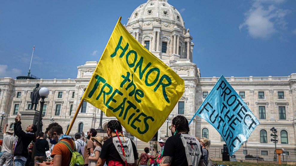 People protesting with flags that say "Honor the Treaties" and "Protect the Future"