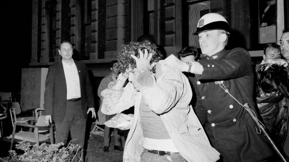 Black and white photo of a police officer removing a protester from a building.