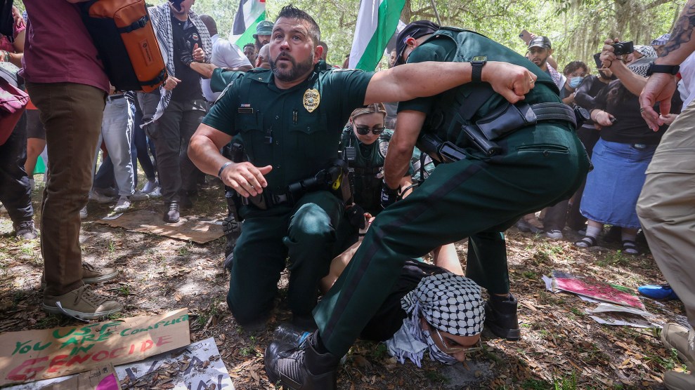 Three police officers arresting a protester who is pinned on the ground.