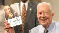 President Jimmy Carter smiling, holding a book.