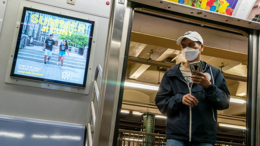 Someone in a N95 entering a NYC subway, with sign saying "CUNY in Summer" next to it