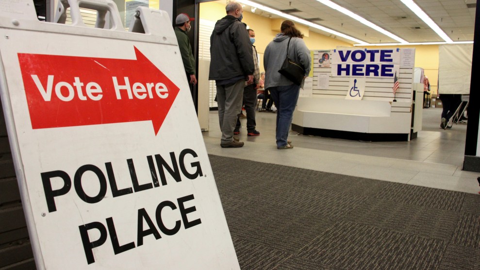 A sign that "Vote here, polling place," with people in line. There is a disability-wheelchair symbol too.