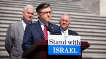 Mike Johnson in front of a podium that says "Stand with Israel"