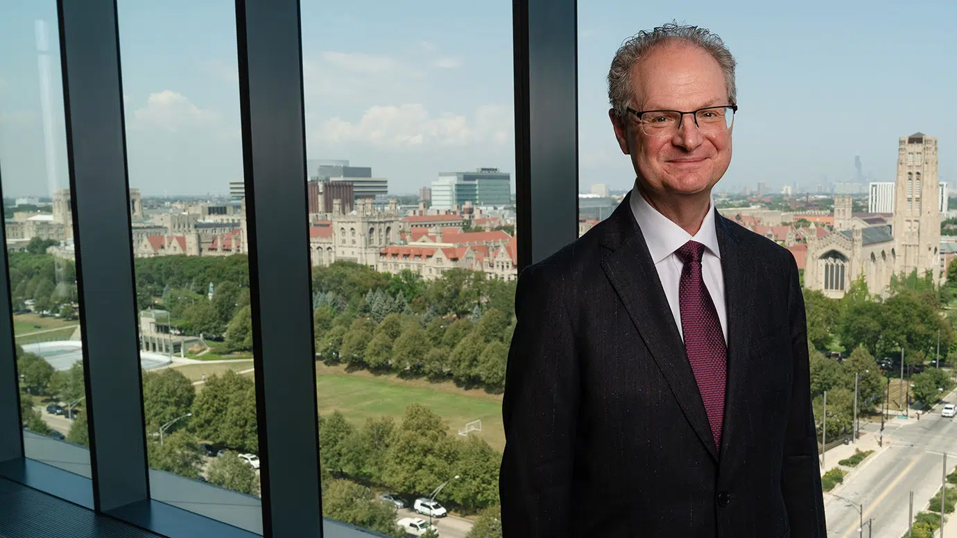 Portrait of man in a suit standing by a window.