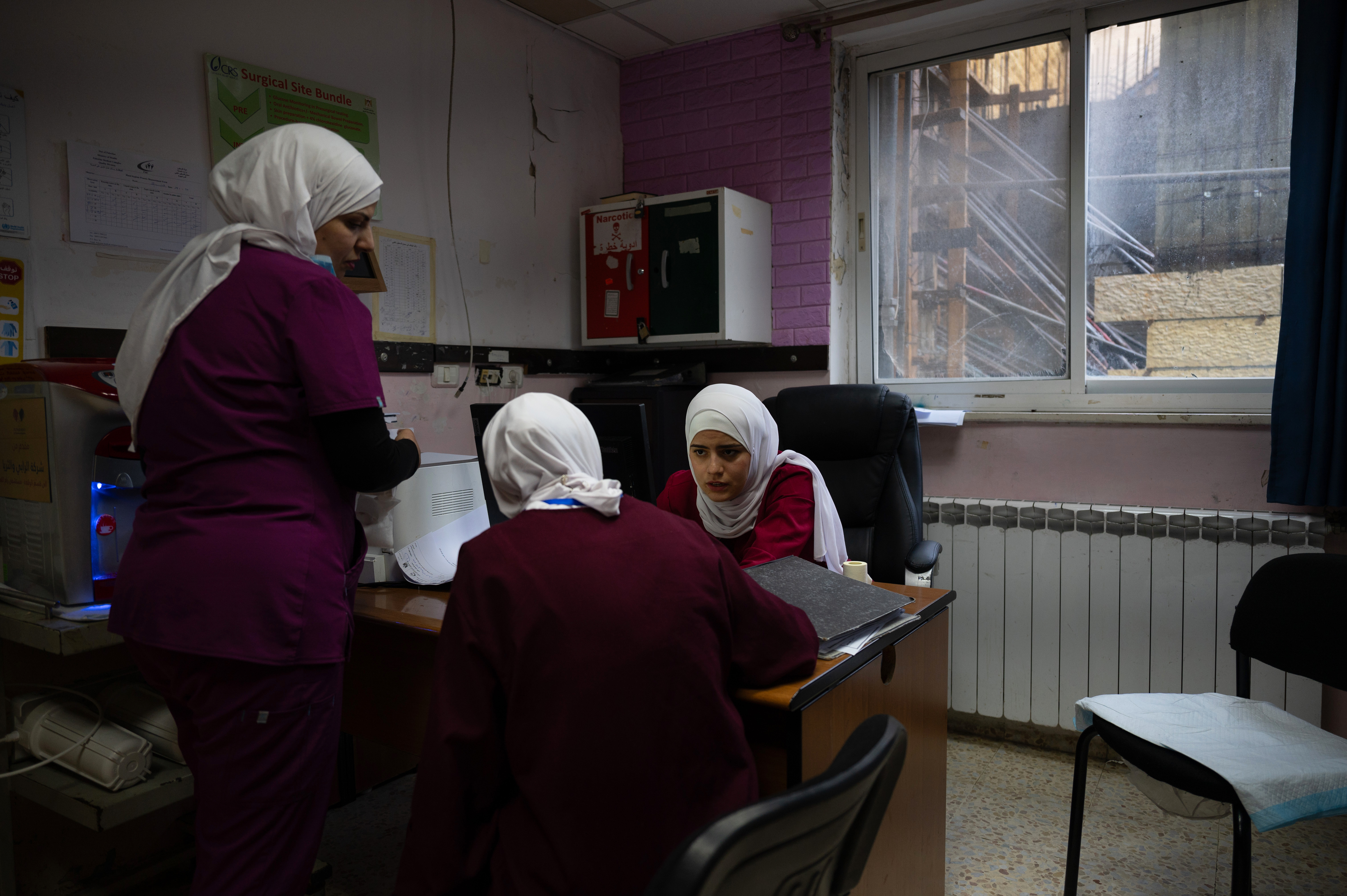 Three nurse talk in a hospital office.