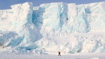 A man walks on a glacier in the Arctic.