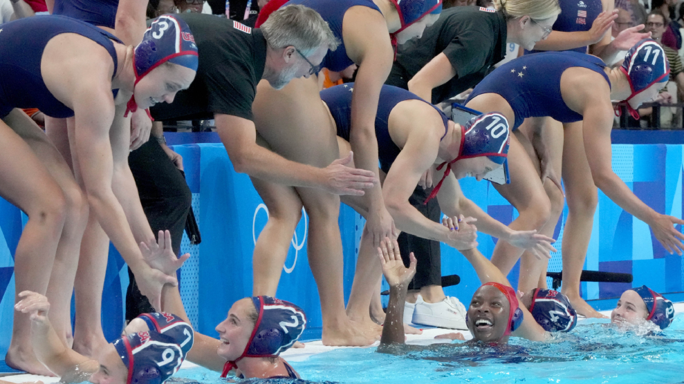 Members of the US women's water polo team celebrate with teammates.