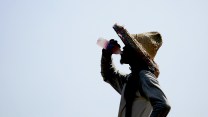 A worker on a roof pauses to take a drink amid high heat