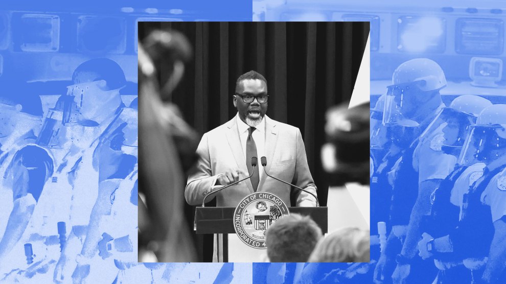 A photo illustration shows Chicago Mayor Brandon Johnson delivering a speech at a podium with the City of Chicago seal, while flanked by press. The image is superimposed over a backdrop of riot police in helmets and face shields, rendered in a high-contrast blue hue.