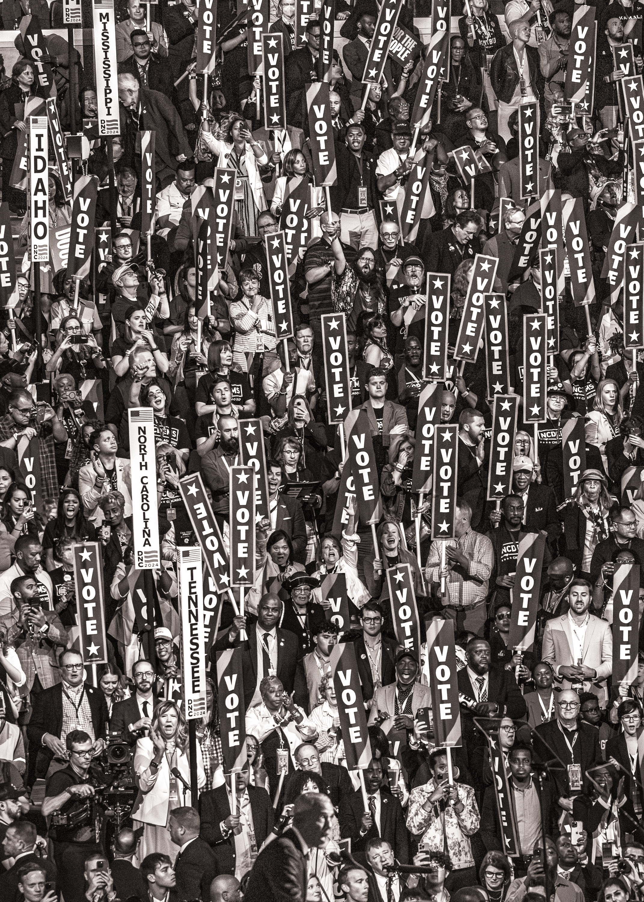 Black and white photo of the crowd at the DNC holding signs that read "VOTE."