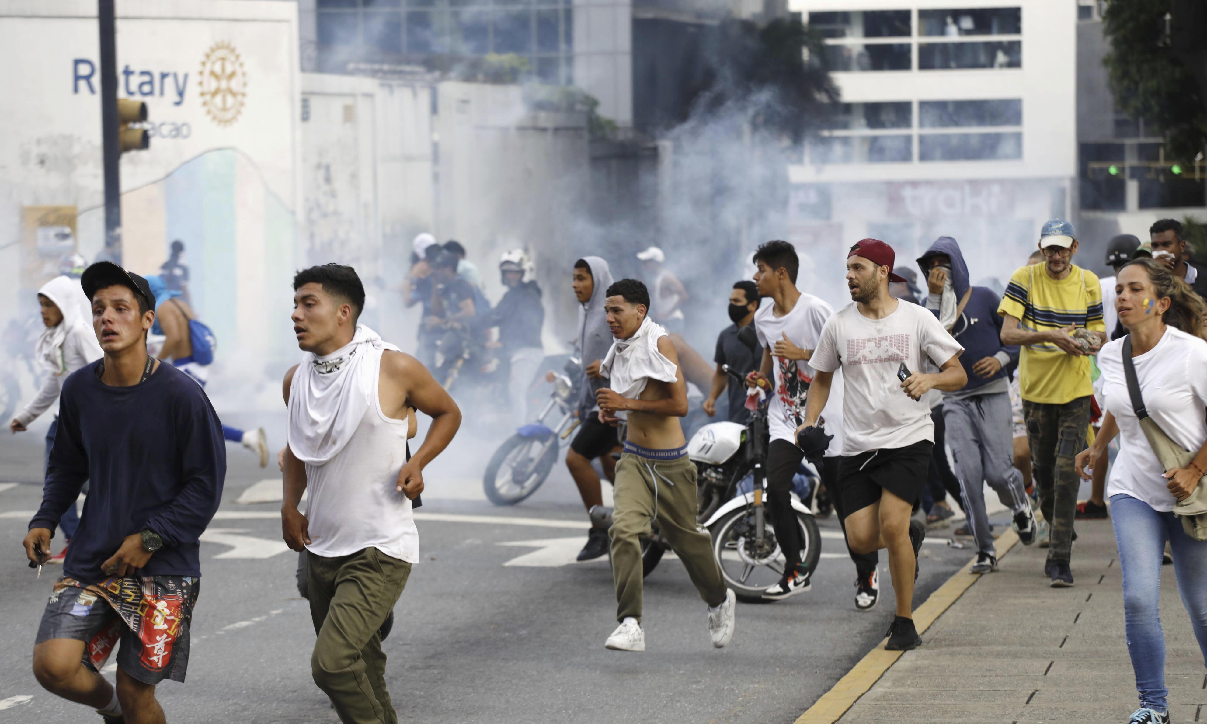 Protestors try to run away from tear gas