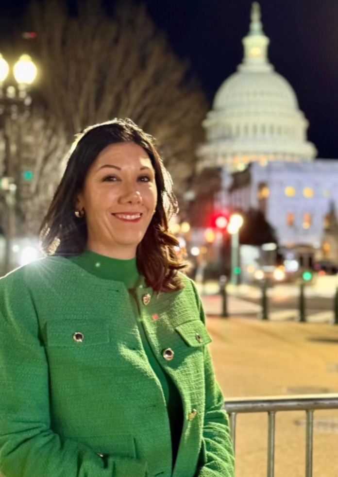 Woman standing outside at night with the United States Capitol building behind her.