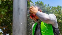 a man in Florida stands under a cold show during a heat advisory