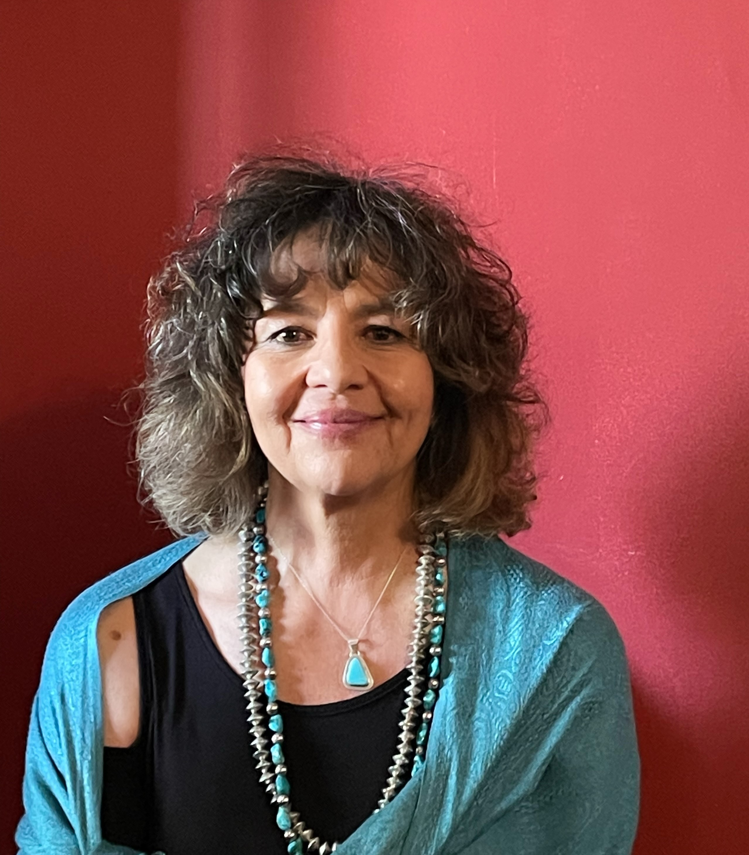 Portrait of a woman smiling against a red wall.