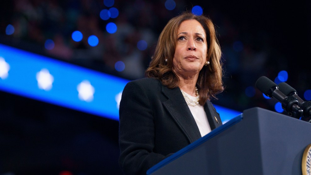 Kamala Harris stands behind the lectern, pausing during a speech before a packed arena.