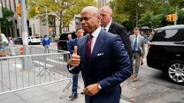 New York Mayor Eric Adams gives a thumbs up as he walks from a black SUV.