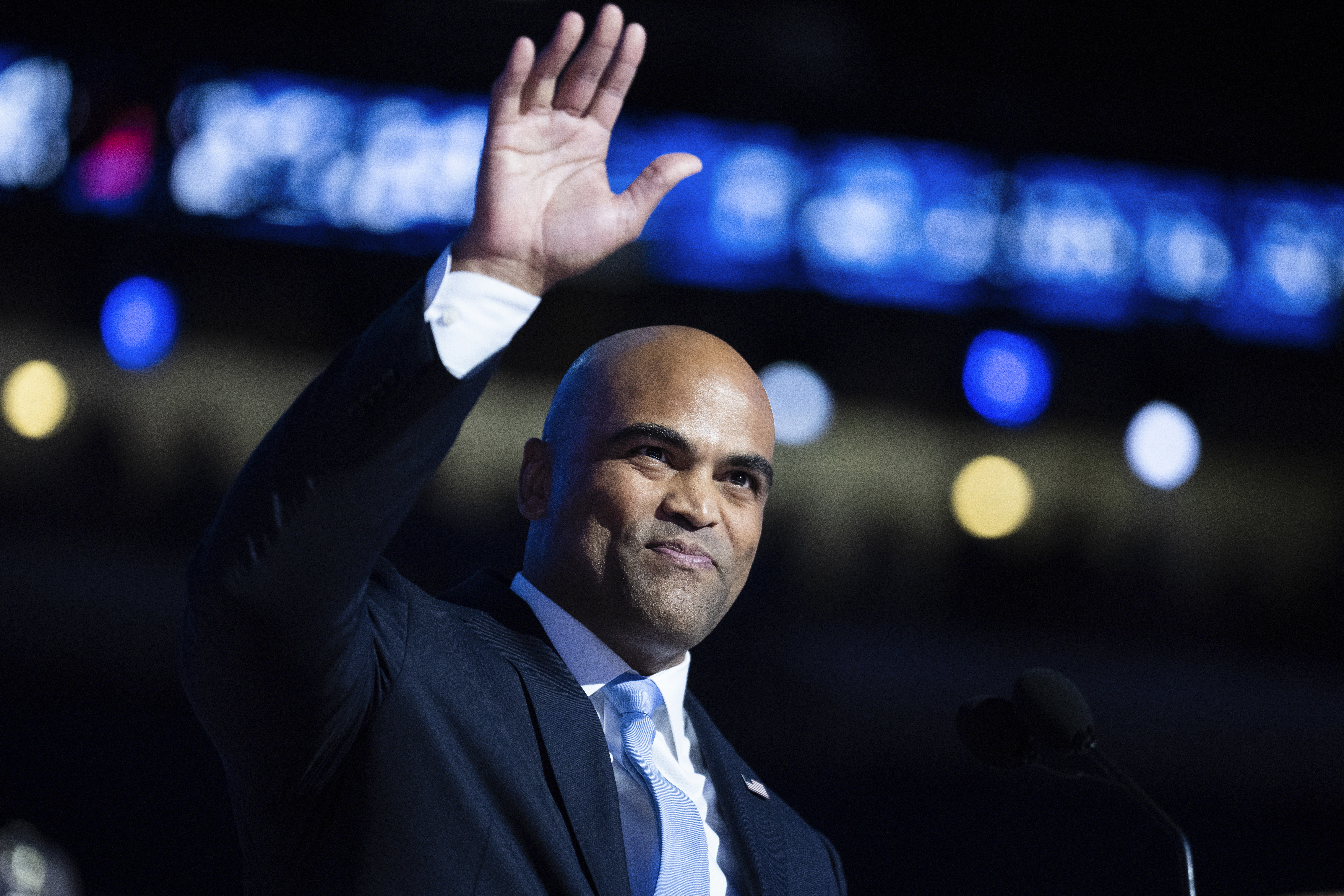 Rep. Colin Allred smiles and waves to a crowd, speaking on stage at the DNC in Chicago. 