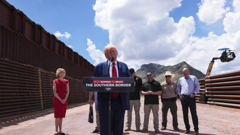 Donald Trump stands behind a podium by the Southern border wall